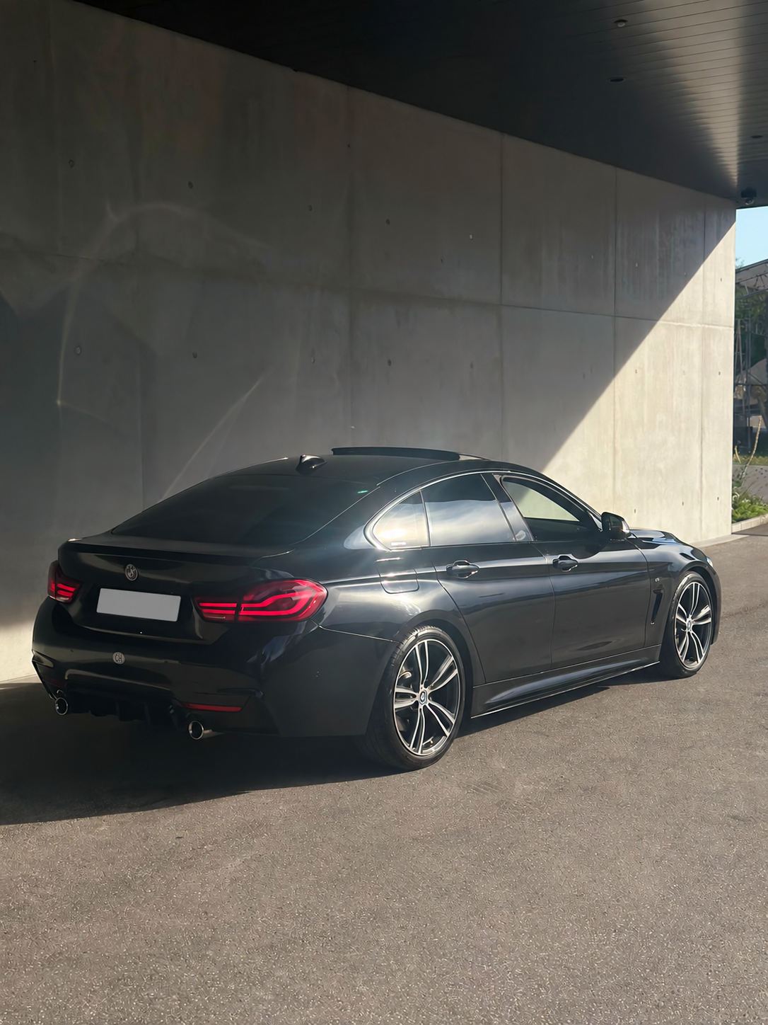 BMW 435i xDrive Gran Coupé M Sport — rear three-quarter view in front of a concrete wall